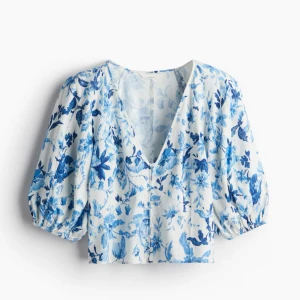 Blommig blus med puffärmar - Säljer en vit blus med blått blommönster. Blusen har trekvarts puffärmar och knappar framtill. 