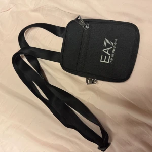 EA7 Emporio Armani - Snygg och praktisk svart axelväska från EA7 Emporio Armani. Väskan har en justerbar axelrem och dragkedja för säker förvaring. Perfekt för att bära med sig det viktigaste på ett stilfullt sätt. 