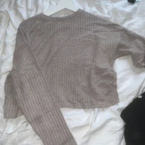 Beige ribbad tröja  - Supermjuk och ribbad beige tröja från Stradivarius. Modellen är croppad med lång ärm och rund halsringning. Perfekt för lager-på-lager och chill dagar. Materialet är stickat och känns riktigt skönt mot huden. Ett litet hål i vid halsen (se bild)