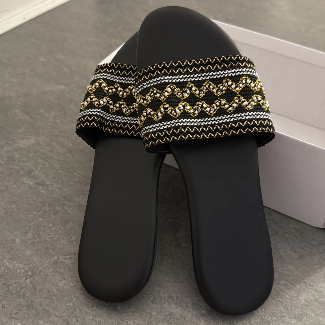 Två par svarta sandaler med mönster