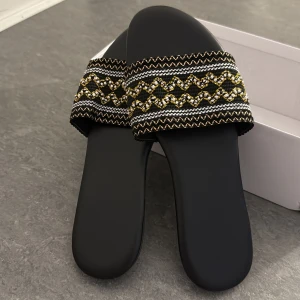Två par svarta sandaler med mönster - Säljer två par snygga svarta sandaler i storlek 39 och 40. Ena paret har bred rem med broderat mönster i guld, vitt och svart, medan det andra paret har en stilren design med strukturmönstrad yta och öppna sidor. Båda har platt sula och öppen tå, perfekta för sommaren.