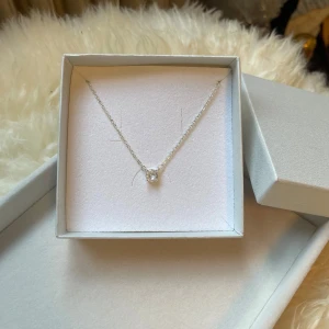 Silverhalsband med klar sten - Ett stilrent halsband i silver med en tunn kedja och en rund, klar sten i mitten. Perfekt för dig som gillar minimalistiska smycken med en touch av elegans. Redo att ges bort eller användas direkt.