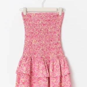 Rosa mönstrad sommarklänning - Supersöt rosa klänning med smock upptill och volang i kjolen. Klänningen har ett paisleyinspirerat mönster i rosa och ljusgult, perfekt för varma dagar. Ärmlös och med en figurnära passform upptill som ger en feminin siluett.