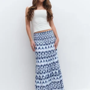 Blåvit långkjol med mönster - Supersnygg långkjol i blått och vitt med ett unikt mönster och smockad midja. Kjolen har flera volanger och ett flowigt fall som ger en chill och bohemisk vibe. Perfekt för dig som vill sticka ut med en cool och bekväm stil.