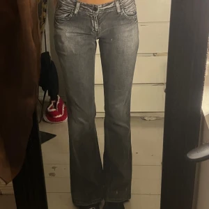 Levis 572 grå bootcut jeans - Grå jeans från Levis modell 572 med bootcut passform. Snyggt slitna detaljer, klassiska femficksmodellen och låg midja. Jeansen har markerade sömmar och är tillverkade i jeansmaterial med en cool tvättad look.
