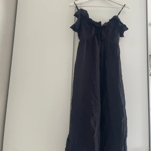 Svart långklänning från H&M - Supersnygg svart långklänning från H&M med tunna axelband och volangdetaljer upptill. Klänningen har en flowy passform och är tillverkad i ett lätt material som känns luftigt. Perfekt för sommarkvällar när du vill känna dig både chill och stilren.