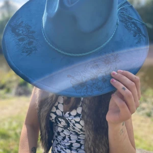 Blå cowboyhatt med blommönster - Westernstil möter feminin elegans i denna rancherhatt med bränd design föreställande havssködpaddor och tropiska blommor. 