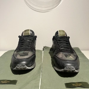 Valentino Rockrunner sneakers camouflage - Tvärfeta Valentino Rockrunner sneakers i svart och grön camouflage . Skorna är i väldigt bra skick och ha är inga defekter alls. Dem är perfekta till hösten och vintern då dem är lite mer robusta än vanliga sneakers. Storleken är 41 men passar bättre om du har 42, kan i vissa fall även passa 43. Dustbags ingår. Tveka inte på att ställa fler frågor!