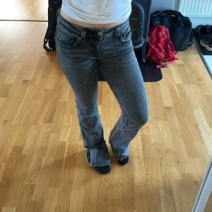 Grå bootcut jeans från Perfect Jeans Gina Tricot - Snygga grå jeans från Gina Tricot i bootcut-modell. Jeansen har klassisk femficksdesign, normalhög midja och är tillverkade i ett stretchigt denimtyg som sitter skönt. Perfekta för dig som gillar en retroinspirerad look med utsvängda ben. Knappar på fickorna bak.