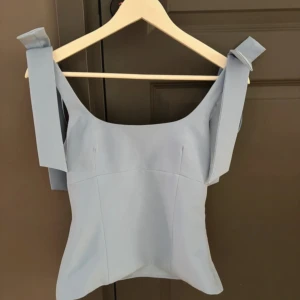 Ljusblå topp med rosett från Zara  - Supersöt topp med rosetter från Zara i xs. Toppen har aldrig använts, prislapp finns dock inte kvar, men den är då i utmärkt skick och säljes enbart pga fel storlek💗