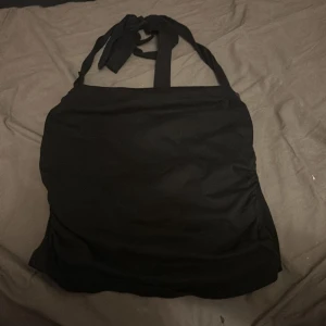 Svart halterneck linne från SHEIN - Svart halterneck linne från SHEIN med knytband i nacken. Toppen är ärmlös och har en enkel, stilren design som passar perfekt till jeans eller kjol. Mjuk och stretchig känsla tack vare bomullsblandning. Snygg och basic för en clean look.