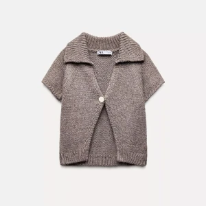 Beige stickad kofta från Zara - Kortärmad stickad kofta från Zara i beige nyans. Koftan har en bred krage, en knapp framtill och ribbade kanter. Perfekt för lager-på-lager och en chill, avslappnad stil.