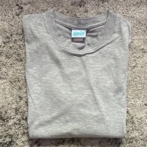 Grå basic t-shirt från KeyOut - Enkel och stilren grå t-shirt från KeyOut med rund halsringning. Perfekt för en clean och avslappnad look. Tillverkad i mjuk bomull som känns skön mot huden. Passar till allt och är ett måste i garderoben.