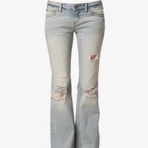 Ljusblå bootcut jeans med slitningar - Säljer ett par ljusblå as snygga bootcut jeans med snygga slitningar och hål på knäna. Jeansen har låg midja och klassisk femficksdesign. Storlek 25/32, pris kan diskuteras
