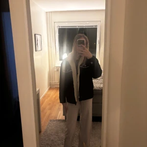 Svart teddyjacka från Monki XS - Svart teddyjacka från Monki i storlek XS med mysigt vit foder och krage i teddy. Jackan har två bröstfickor med knappar och synliga sömmar i kontrastfärg. Perfekt för kalla dagar och riktigt snygg till både jeans och mjukis.