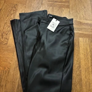 Svarta PU-byxor från Bikbok, skinnimmitation - Svarta byxor i snyggt PU-material(skinnimmitation) från Bikbok. Modellen har låg midja och raka ben med klassiska fickor fram och bak. Helt nya med lapp kvar, nypris 599. Mitt pris 149kr. Sista bilderna är från Bik Boks hemsida.