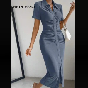 Blå långklänning med slits - Supersnygg blå långklänning med tight passform och korta ärmar. Klänningen har knappar framtill, rynkade detaljer längs magen och en slits nertill som ger en extra cool touch. Perfekt för dig som gillar en stilren och trendig look.