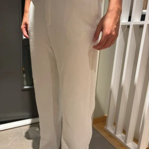 Vita mjukisbyxor från Bershka - Vita mjukisbyxor från Bershka i storlek M. Byxorna har resår i midjan, raka ben och en bakficka. Tillverkade i mjukt bomullsmaterial och har en liten broderad logga framtill. Perfekta för en chill och avslappnad look.