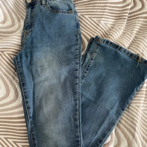 Blå jeans från Vila - Snygga blå jeans från Vila i klassisk tvätt med utsvängda ben. Bra skick förutom nere vid benen (se sista bild) 