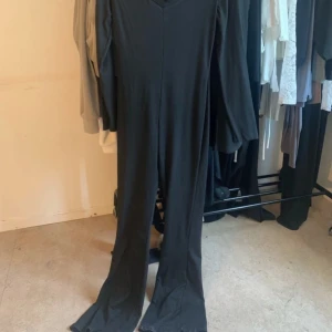 Bodysuit - Svart Bodysuit med långa ärmar och vida ben. Enkel och stilren design, perfekt för dig som gillar en clean look. Mjuk och stretchig känsla i materialet som gör den bekväm att bära hela dagen.