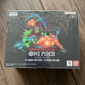 One Piece Card Game OP-06 : Wings of the Captain.(Ending) - Upptäck One Piece-världen med detta samlarbox! Innehåller 24 booster packs med 12 kort i varje, fyllda med episka karaktärer och coola foil-kort. Perfekt för fans av manga, anime och strategiska kortspel. Skapa din egen besättning och utmana vänner!