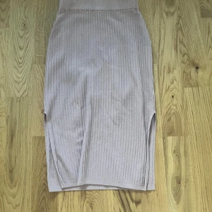 Beige ribbad kjol från Weekday XS - Säljer en beige ribbad kjol från Weekday i storlek XS. Kjolen är midilång med slits på båda sidor och har en tight passform. Perfekt för dig som gillar en enkel men snygg look. Materialet är mjukt och stretchigt för extra komfort.