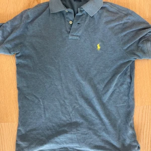Ljusblå pikétröja från Polo Ralph Lauren - Snygg ljusblå pikétröja från Polo Ralph Lauren i modellen Custom Fit. Tröjan har korta ärmar, klassisk krage och två knappar framtill. Den ikoniska gula logon är broderad på bröstet. Perfekt för en chill och stilren look. Storlek S, 10/10. Fler frågor tas i pm! /Neo💫