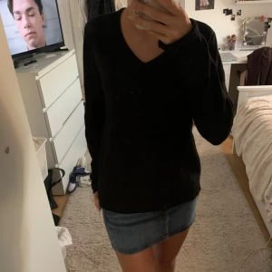 Svart v-ringad stickad tröja - Svart stickad tröja med v-ringning och långa ärmar. Enkel och stilren modell som är lätt att matcha med olika outfits. Tröjan har en normal passform och är perfekt för kyligare dagar.