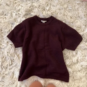 Vinröd stickad tröja från Gina Tricot - Mysig vinröd stickad tröja från Gina Tricot med korta ärmar och rund halsringning. Perfekt för lager-på-lager och passar till både jeans och kjol. Enkel och stilren design som funkar året runt.