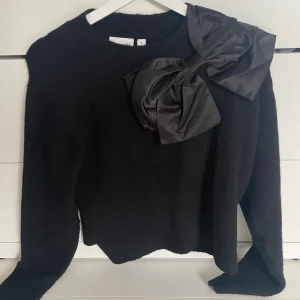 Svart stickad tröja med stor rosett - Ursnygg svart stickad tröja från Kappahl med en stor rosett, storlek S och knappt använd 