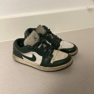 Nike Air Jordan 1 Low gröna/vita - Säljer ett par Nike Air Jordan 1 Low i mörkgrönt och vitt skinn. Klassisk Jordan-logga på hälen och Jumpman på plösen. Lågt skaft, snörning och rund tå. Perfekta för dig som gillar streetwear och vill sticka ut med en ikonisk sneaker. Köpta på kicks n stuff i Göteborg 