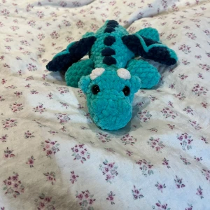 Virkad turkos drake  - Supersöt virkad drake i färgen turkos. Precis som många av mina andra figurer innehåller dessa drakar säkerhetsögon vilket inte rekommenderas för barn under 3 år.🩵