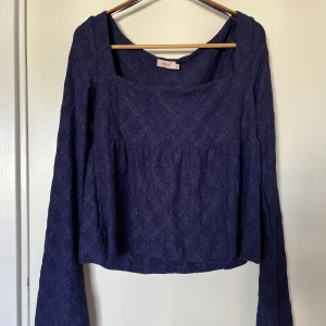 Mörkblå spetstopp från Nelly - Supersöt mörkblå topp från Nelly med långa klockformade ärmar och fyrkantig ringning. Blusen är i spetsmaterial och i peplummodell. Använd 1 gång. Säljer en likadan i rött också! Passar s/m. 