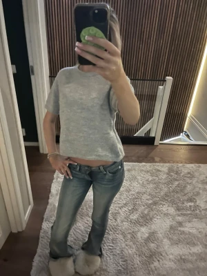 Ljusgrå kortärmad topp - En enkel och stilren ljusgrå topp med korta ärmar och rak passform. Toppen är croppad och har en mjuk känsla, perfekt att matcha med jeans eller kjol. Inga synliga loggor eller mönster.