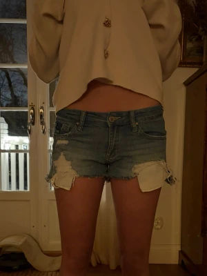 Blå slitna jeansshorts med fransar - Lågmidjade jeansshorts