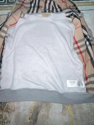 Burbery kofta  - Snygg grå hoodie från Burberry med dragkedja och klassiskt rutigt foder i huvan. Tillverkad i mjukt bomullsmaterial och har två fickor framtill samt ribbade muddar.  