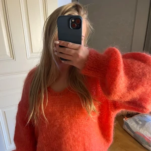 Oversized coralfärgad stickad tröja - Säljer en fluffig och oversized stickad tröja i en rosa färg. Tröjan har långärmade, breda ärmar och en mjuk, lite luddig yta. Passformen är loose och den har en rundad halsringning. Säljer pga att den inte kommit till användning, alldrig använd 💕kom gärna med prisförslag, nypris 2000 kr 