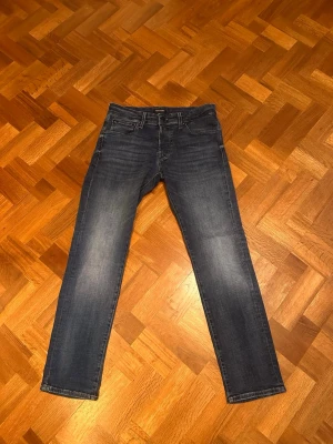 Mörkblå jeans från Jack&jones  - Snygga mörkblå jeans med raka ben och klassisk femficksdesign. Jeansen har en lätt tvättad look med subtila slitningar på framsidan. Perfekta till vardags och passar till det mesta. Tillverkade i mjukt och slitstarkt bomullsmaterial. Skriv vid funderingar! 