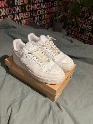 Nike Air Force 1 vita sneakers - Klassiska Nike Air Force 1 sneakers i helvitt skinn med rund tå och snörning. Modellen har en platt sula och diskret Nike-logga på sidan. Perfekta för dig som gillar en clean och tidlös stil. Billigare vid snabb affär. Storlek 43. Tvättas innan de fraktas