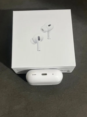 Apple AirPods Pro 2 - Snygga vita Apple AirPods Pro med stilren design och laddningsetui. Trådlösa in-ear-hörlurar med silikonproppar för bra passform och brusreducering. Perfekta för musik, samtal och träning. Kommer i originalförpackning.