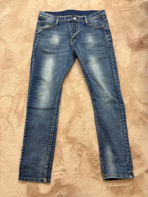 Armani Jeans - Snygga blå jeans med raka ben och slitna detaljer på låren och knäna. Klassisk femficksmodell med kontrastsömmar och knappgylf. Perfekta för en avslappnad och trendig look.