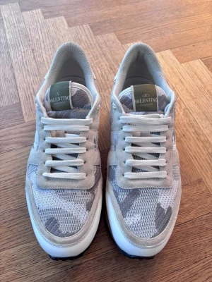 Valentino Garavani Rockrunner sneakers - Säljer ett par Valentino Garavani Rockrunner sneakers i beige och grått med camouflagemönster. Box i camo medföljer samt skofodral och skosnören, samt ett kuvert som autentiserar skornas äkthet. Köpta från hemsidan. Pris kan diskuteras! Kvitto finns