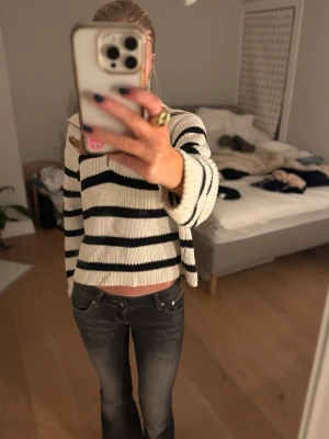 Randig stickad tröja! - Stickad tröja i vitt med svarta horisontella ränder och en snygg krage. Tröjan har en avslappnad passform och långa ärmar, perfekt för en trendig och bekväm look. Passar till jeans eller kjol för en cool stil! Pris kan diskuteras 💕💕