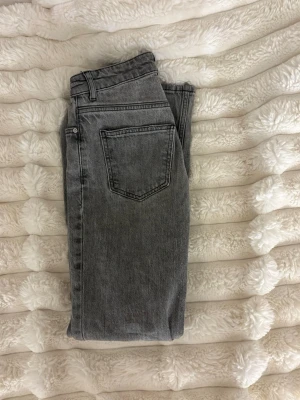 Grå jeans från Gina tricot  - Snygga grå jeans från g perfect jeans med klassisk femficksdesign och dragkedja. Jeansen har en rak passform och är tillverkade i mjukt bomullsmaterial. Perfekta för en avslappnad och trendig look.