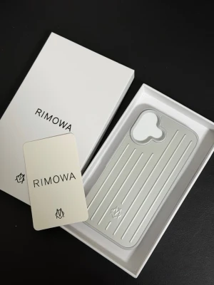 Rimowa iPhone 16 silverfärgat mobilskal - Snyggt och stilrent mobilskal från Rimowa i silverfärgad aluminium med klassiska räfflade linjer. Skalet har en unik design för kameran och är lätt men tåligt. Perfekt för dig som vill ha ett exklusivt och modernt skydd till din iPhone.