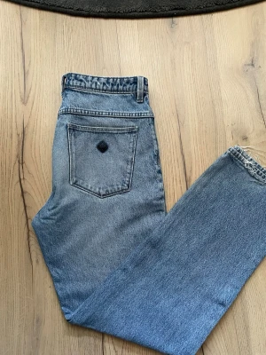 Blå jeans från Abrand - Snygga blå jeans med hög midja och raka ben. Klassisk femficksmodell med en unik detalj på bakfickan. Jeansen har bälteshällor och är tillverkade i ett slitstarkt bomullsjeansmaterial. Perfekta för en avslappnad och trendig look.