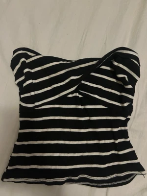 Randig svartvit bandeau topp - Snygg bandeau topp i svart och vitt med horisontella ränder. Toppen är ribbad och axelbandslös, perfekt för en trendig look. Materialet känns stretchigt och sitter tight mot kroppen.