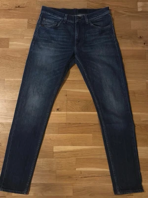 Tiger of sweden jeans - Snygga mörkblå tiger of sweden jeans med klassisk femficksdesign och läderpatch bak i midjan. Jeansen har en rak passform med lätt slitning och är tillverkade i bomullsdenim. Perfekta för en stilren och avslappnad look. Nypris runt 1500.