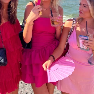 Rosa volangklänning med omlott - Säljer en snygg kort rosa klänning med volanger och omlott-detalj. Klänningen är axelbandslös och har en figurnära passform.