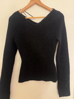 Svart stickad tröja med v-ringning - En svart, figurnära stickad tröja med v-ringad hals och långa ärmar. 